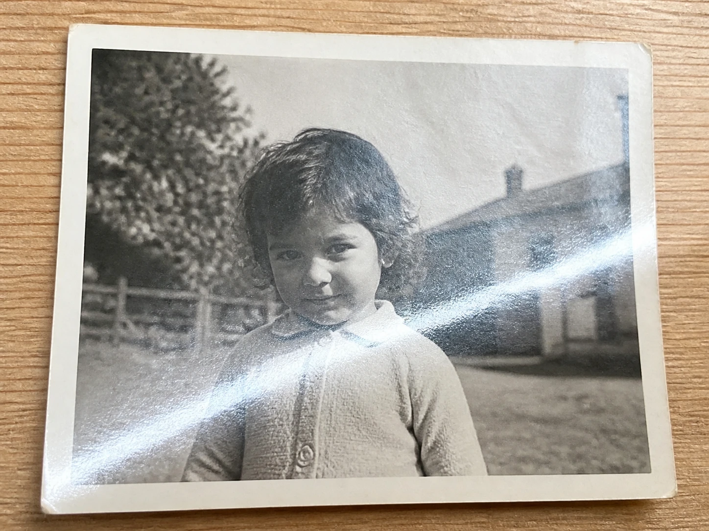 An old paper print rephotographed with a phone, glare and grain across the small face